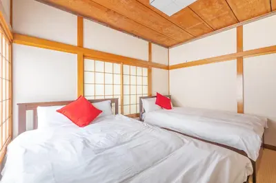 two beds with red pillows in a room with windows at SKY GATEスカイツリー徒歩3分の貸切ヴィラ/成田羽田直通/浅草徒歩15分 in Tokyo