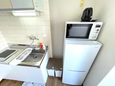 a microwave on top of a refrigerator in a kitchen at Gest Residence EDORIVER Airport Line Self check in in Tokyo