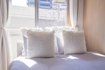 a bed with white pillows in front of a window at walk to JR Shibuya sta.-EoE3 in Tokyo