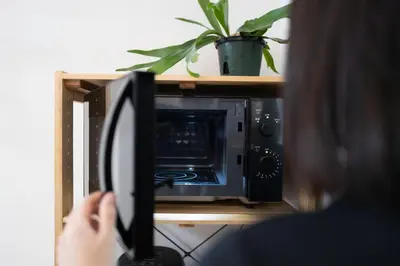 a woman is taking a picture of a microwave at Kaku Studio Apartment Ikebukuro in Tokyo