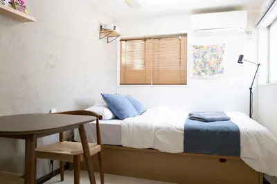 a bedroom with a bed and a table and a window at Kaku Studio Apartment Ikebukuro in Tokyo