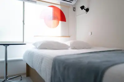 a white bedroom with a bed with a window at Kaku Studio Apartment Ikebukuro in Tokyo