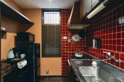 a kitchen with a sink and a red tiled wall at Retro Style Japanese House 10-min walk to Asakusa in Tokyo