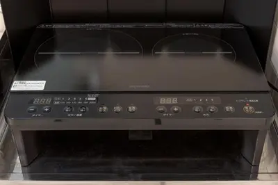 a black stove top oven sitting in a cabinet at Kamata Smile House - \u84b2\u7530\u3059\u307e\u3044\u308b\u30cf\u30a6\u30b9 in Tokyo