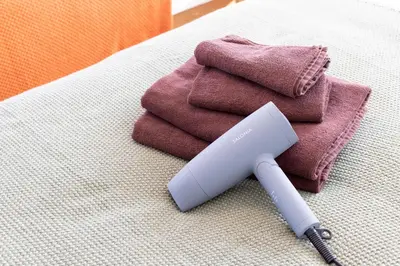 a hair dryer sitting on a bed with towels at Kamata Smile House - \u84b2\u7530\u3059\u307e\u3044\u308b\u30cf\u30a6\u30b9 in Tokyo