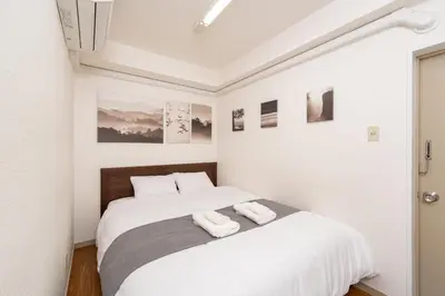 a white bedroom with a bed with two towels on it at CoCoHouse Asakusa - SkyTree View, 72\u33a1 in Tokyo