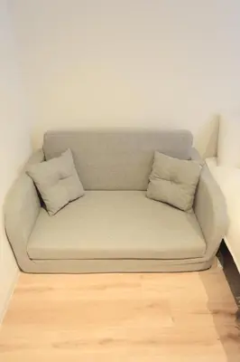 a couch with two pillows sitting on a wooden floor at 4min walk to JR Yoyogi Sta 8min to Shinjuku MGW in Tokyo