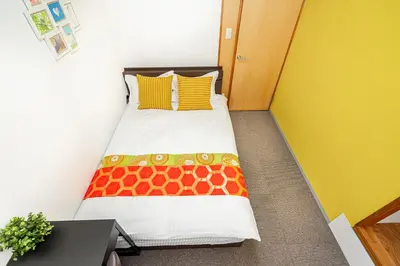 a small bedroom with a bed with a giraffe blanket at \u4e21\u56fd\u99c5\u524d in Tokyo
