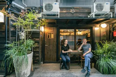 a man and a woman sitting at a table outside a building at Hotel Suzumeya Tsukiji \u30db\u30c6\u30eb\u3059\u305a\u3081\u3084\u7bc9\u5730 in Tokyo
