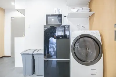 a person standing next to a washing machine in a room at 1min walk to Higashi Shinjuku sta 8PPL Shinjuku Gyoen\u4e36 National Garden\u4e36 Kabukicho\u4e36 Shinjuku Station\u4e36 Golden Gai\u4e36 Tokyo Metropolitan Government Building YYoQA in Tokyo