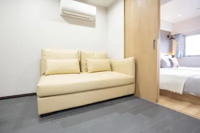 a white couch in a room with a bed at 1min walk to Higashi Shinjuku sta 8PPL Shinjuku Gyoen\u4e36 National Garden\u4e36 Kabukicho\u4e36 Shinjuku Station\u4e36 Golden Gai\u4e36 Tokyo Metropolitan Government Building YYoQB in Tokyo