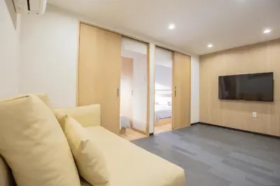 a living room with a white couch and a television at 1min walk to Higashi Shinjuku sta 8PPL Shinjuku Gyoen\u4e36 National Garden\u4e36 Kabukicho\u4e36 Shinjuku Station\u4e36 Golden Gai\u4e36 Tokyo Metropolitan Government Building YYoQB in Tokyo