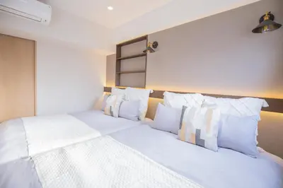 a bedroom with two beds with white sheets and pillows at 1min walk to Higashi Shinjuku sta 8PPL Shinjuku Gyoen\u4e36 National Garden\u4e36 Kabukicho\u4e36 Shinjuku Station\u4e36 Golden Gai\u4e36 Tokyo Metropolitan Government Building YYoQB in Tokyo