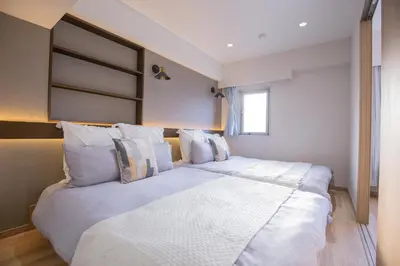 a bedroom with two beds with white sheets at 1min walk to Higashi Shinjuku sta 8PPL Shinjuku Gyoen\u4e36 National Garden\u4e36 Kabukicho\u4e36 Shinjuku Station\u4e36 Golden Gai\u4e36 Tokyo Metropolitan Government Building YYoQB in Tokyo