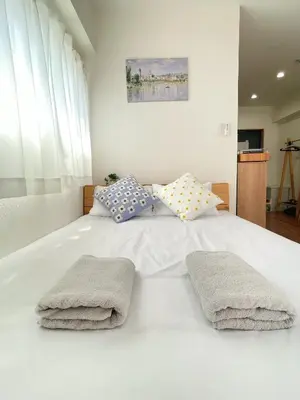 a white bed with two towels on top of it at Home Stroy in Tokyo-VENTI Okachimachi \u6771\u4eac\u5c4b\u8a9e in Tokyo