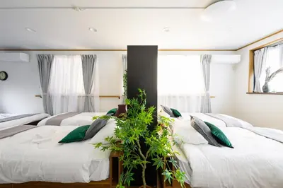two beds in a room with windows and plants at \u6771\u5411\u5cf6\u4e09\u4e01\u76ee\u65c5\u9928 in Tokyo