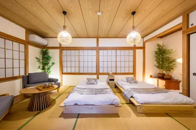 a room with two beds and a couch and windows at \u6771\u5411\u5cf6\u4e09\u4e01\u76ee\u65c5\u9928 in Tokyo