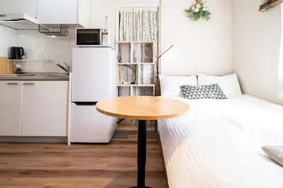 a small room with a table and a white refrigerator at \u76ee\u9ed2\u6075\u6bd4\u5bff\u30a8\u30ea\u30a2 1\u968e One Room Stadio \u76ee\u9ed2\u5ddd\u306b\u8fd1\u3044 in Tokyo