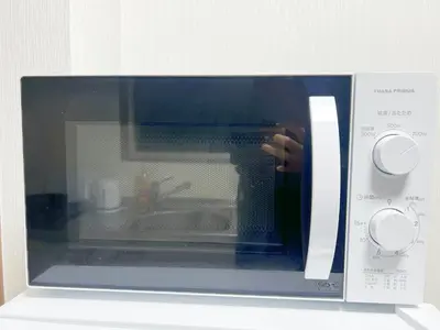 a microwave with a persons hand inside of it at \u6c60\u888b2\u52065\u4eba\u53ef in Tokyo