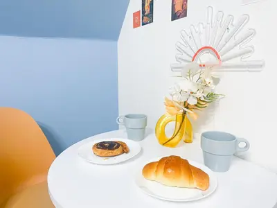 a table with two plates of bread and cups and a vase with flowers at PokaPoka Stay Shinkoiwa R in Tokyo