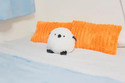 a bird sitting on a bed next to a pillow at PokaPoka Stay Shinkoiwa R in Tokyo