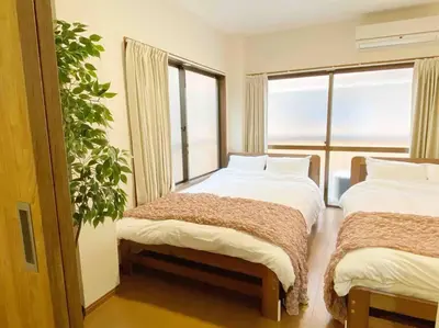 a bedroom with two beds and a large window at SunStay Tachiaigawa 2 in Tokyo