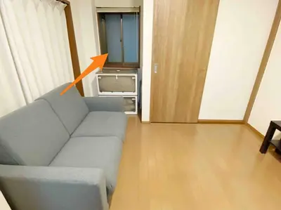 a living room with a gray couch and an orange arrow at SunStay Tachiaigawa 2 in Tokyo