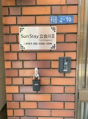 a brick wall with a sign and a lock at SunStay Tachiaigawa 2 in Tokyo