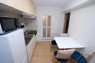 a small kitchen with a white table and a small table and chairs at \u82b1\u5bbf\u65b0\u5bbf HANAYADO SHINJUKU in Tokyo