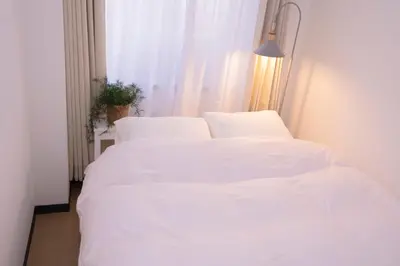 two white beds in a room with a window at \u82b1\u5bbf\u65b0\u5bbf HANAYADO SHINJUKU in Tokyo