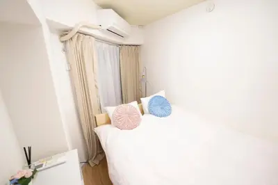 a bedroom with a bed with two pillows on it at \u82b1\u5bbf\u65b0\u5bbf HANAYADO SHINJUKU in Tokyo