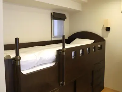 a bedroom with a wooden bed with white sheets at HOTEL BRILLIO ASAKUSABASHI in Tokyo