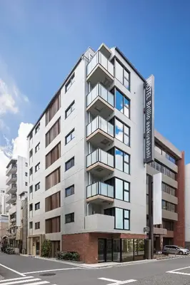 a large white building with balconies on a street at HOTEL BRILLIO ASAKUSABASHI in Tokyo