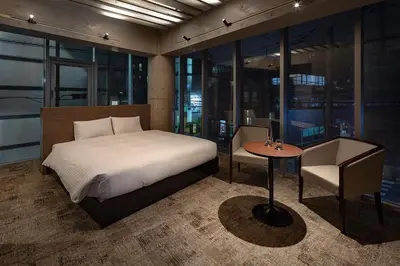 a bedroom with a bed and a table and some windows at The SAUNA Escape Shibuya in Tokyo