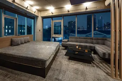 a bedroom with a bed and a couch and windows at The SAUNA Escape Shibuya in Tokyo