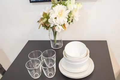 a table with plates and glasses and a vase of flowers at Shinjuku Ryokan Retreat丶Local Tokyo Experience & Short Trips Hub丶walk to Shinjuku station EoE4 in Tokyo