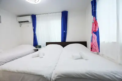 two white beds in a room with a window at Colorful House SKY TREE in Tokyo