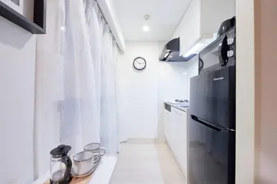 a kitchen with a black refrigerator and white cabinets at Shinjuku Kabukicho Designer's Apartment III in Tokyo