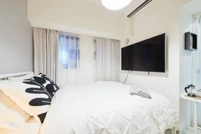 a white bedroom with a bed and a flat screen tv at Shinjuku Kabukicho Designer's Apartment III in Tokyo