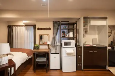 a bedroom with a bed and a desk with a microwave at \u30a2\u30f3\u30c9\u30b9\u30c6\u30a4\u65b0\u5bbf7\u4e01\u76ee in Tokyo