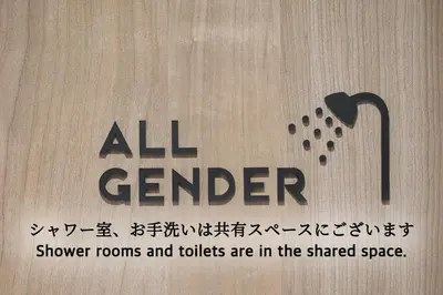 a sign that reads all gender shower rooms and toilets are in the shared space at OHWA hostel minowa station in Tokyo