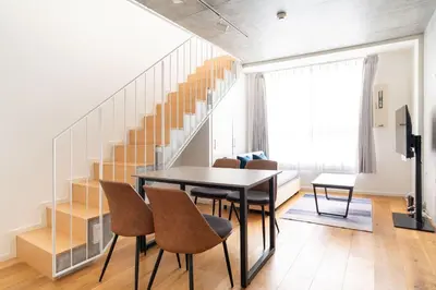 a dining room with a table and chairs and a staircase at Lega land\u4e09\u8ed2\u8336\u5c4bANNEX in Tokyo