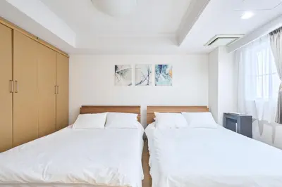 two beds in a bedroom with white walls and a window at K-Large balcony, Luxury 2Bedroom Condo, 101sqm,Max14 PPL,7mins walk to station, Elevator,QuiteArea in Tokyo
