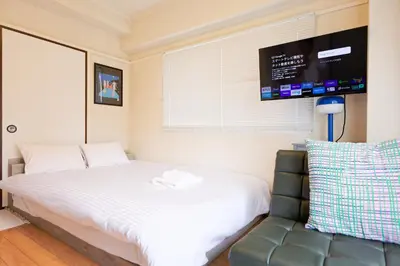a bedroom with a bed and a couch and a tv at Mi-FUJITAKI WASEDA in Tokyo
