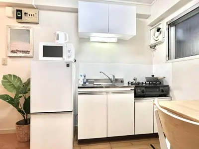 a white kitchen with a sink and a refrigerator at Mi-FUJITAKI WASEDA in Tokyo