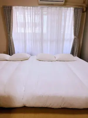 a bed with white sheets and a window at 交通便利 山手線池袋駅 徒歩6分 東池袋駅徒歩3分 2~5人 エレベーター WIFI 新宿/渋谷/銀座/築地/浅草/原宿近い！ in Tokyo