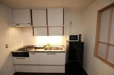 a kitchen with white cabinets and a sink and a refrigerator at \u5357\u6c60\u888b\u6238\u5efa in Tokyo
