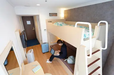 a person sitting in a bunk bed with a laptop at Ryogoku View Hotel in Tokyo