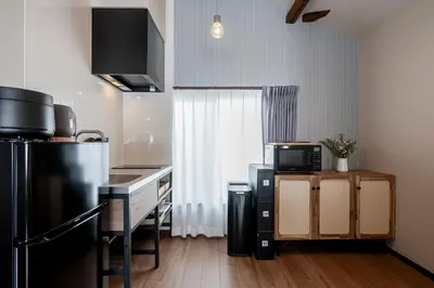 a kitchen with a black refrigerator and a microwave at \u30d9\u30eb\u30d3\u30e5\u30fc\u516b\u5e83 in Tokyo