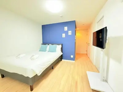 a bedroom with a bed and a blue wall at Base36 in Tokyo